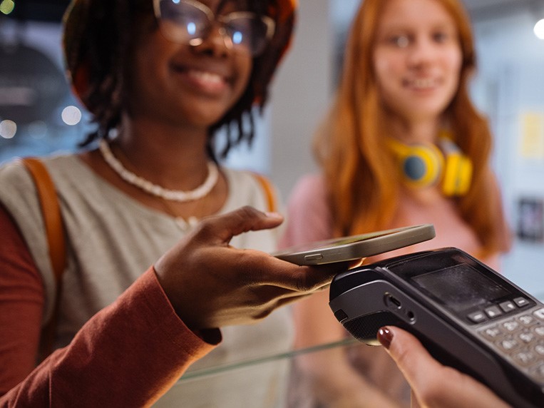 Two female teenagers making a purchase using mobile app on their phone.
