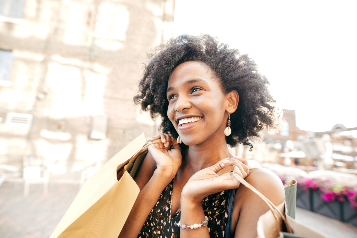 Millennial Aged Woman looking happy shopping and holding bags over her shoulders