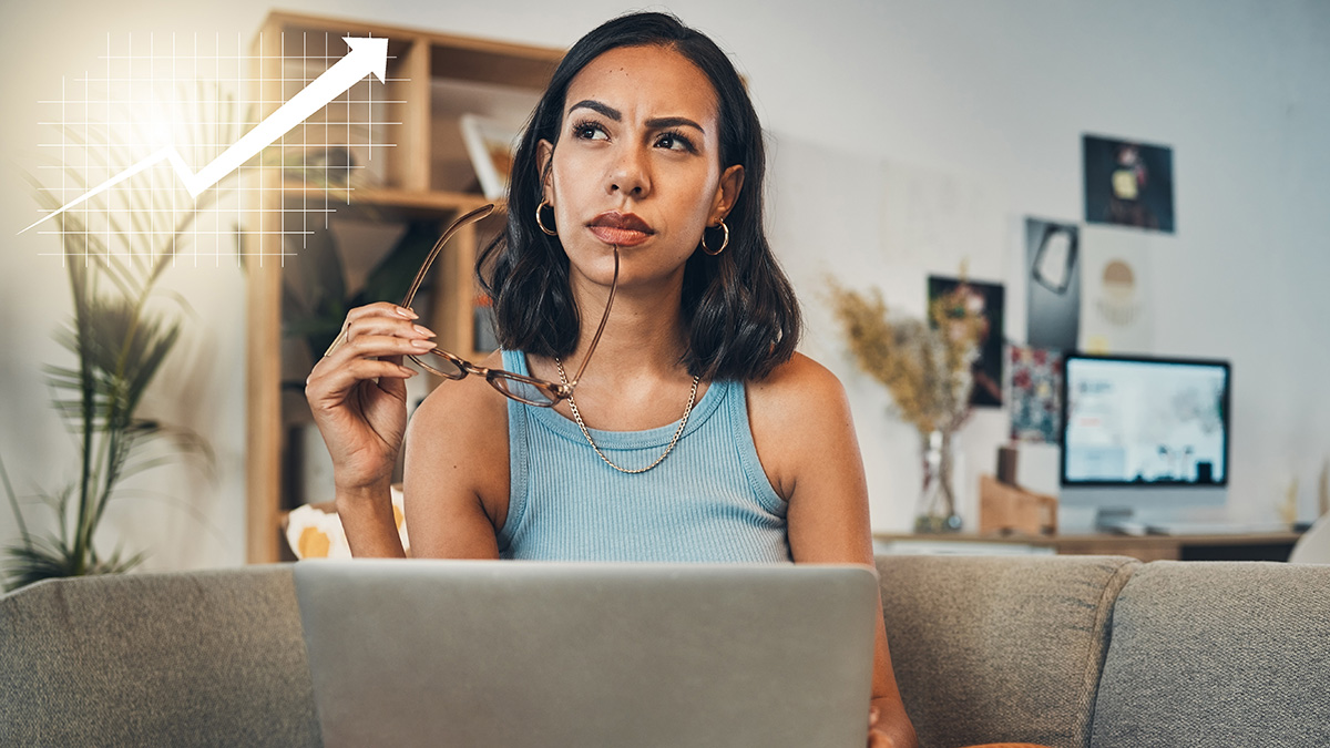 Woman thinking while working on laptop at home with rising graph symbol representing financial growth.