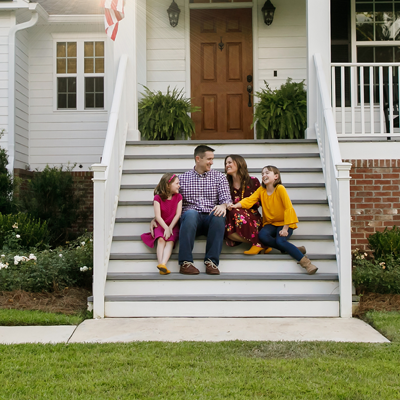 A family sitting on the front steps of their newly financed home, made possible by St. Mary's Bank.