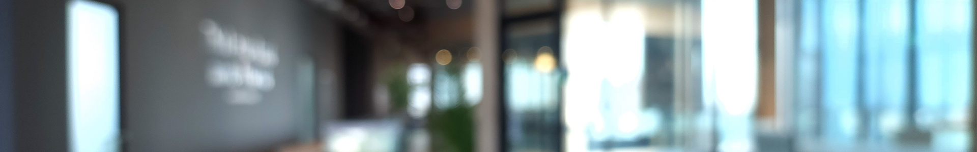 Blurred image of the entrance to an office building with large open glass windows at the front