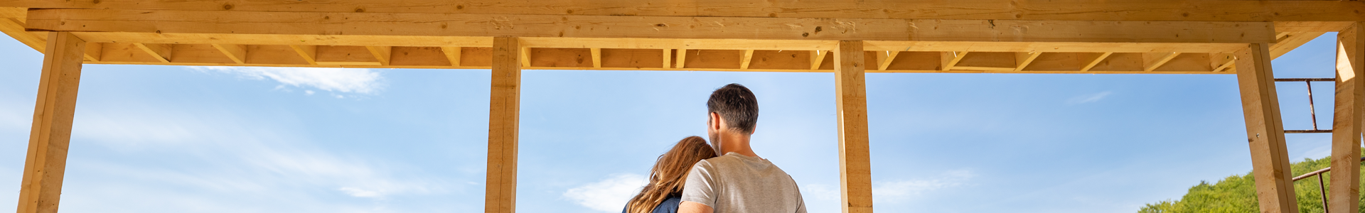 Couple standing together in the carpentry wooden frame of a new home