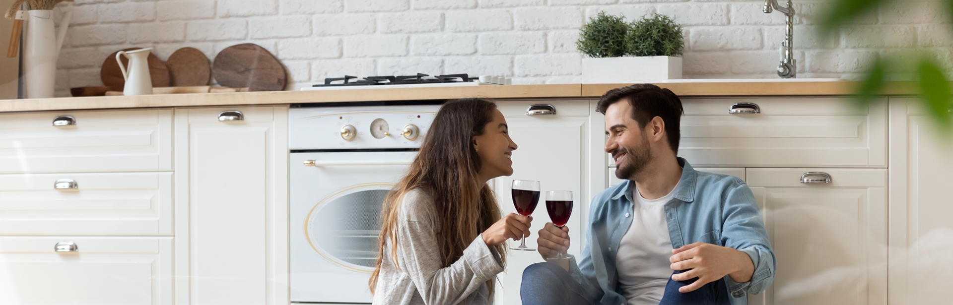 Hello banner young couple in kitchen with wine glasses