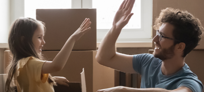 Dad and daughter high-fiving as they unpack boxes in a new home
