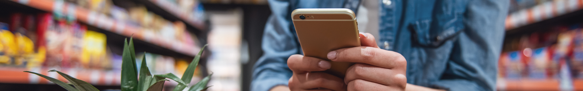 Person shopping in store, in an aisle, looking at their mobile phone