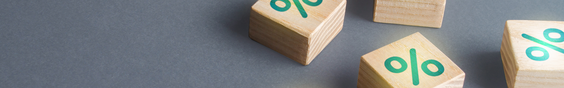 Four wooden cubes with the percentage sign painted on them placed on a grey background